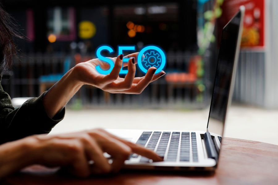 Medical Practice Person using laptop holding the word SEO with a gear icon within the letter 